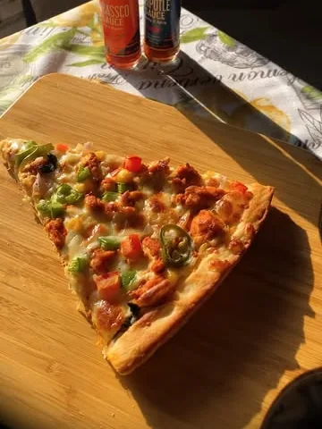 A slice of Sabah Bakers pizza on a wooden board